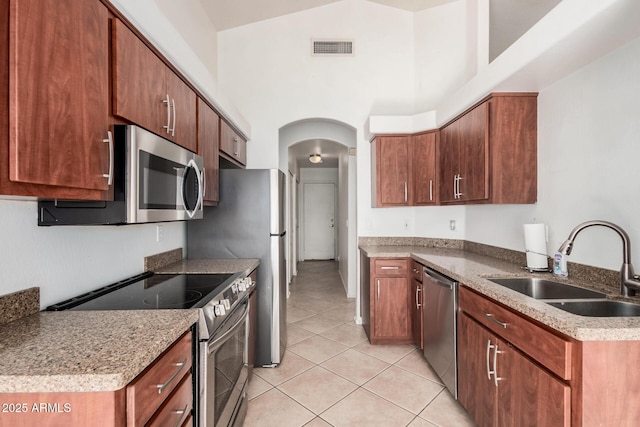 kitchen with sink, light tile patterned floors, a high ceiling, and appliances with stainless steel finishes