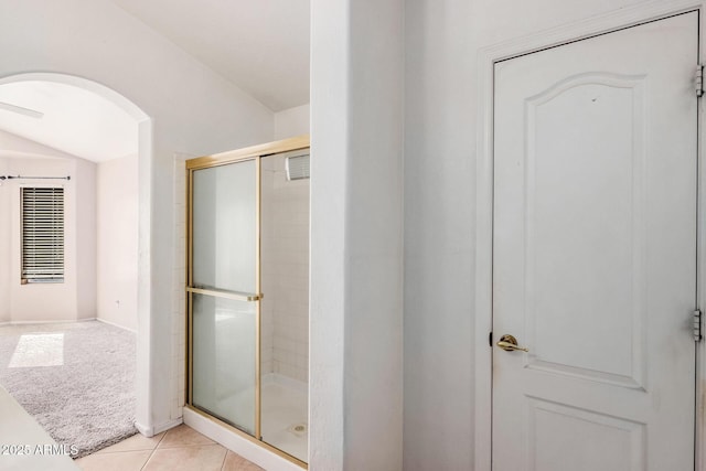 bathroom with tile patterned flooring, vaulted ceiling, and a shower with door