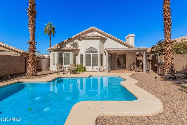 back of house with a fenced in pool and a patio