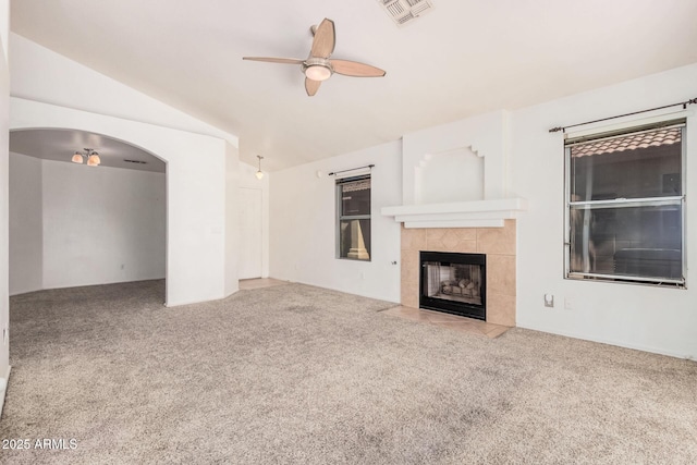 unfurnished living room featuring vaulted ceiling, ceiling fan, carpet floors, and a tile fireplace