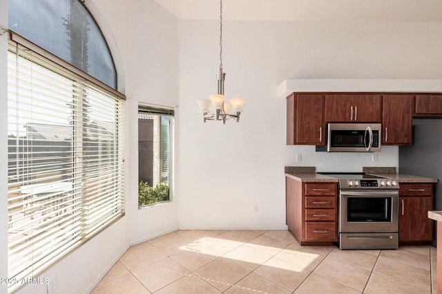 kitchen with light tile patterned floors, hanging light fixtures, stainless steel appliances, a high ceiling, and a notable chandelier