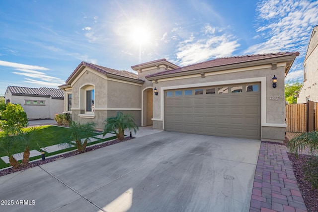 mediterranean / spanish home featuring driveway, an attached garage, a tile roof, and stucco siding