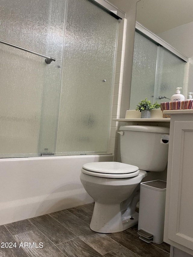 bathroom with toilet and bath / shower combo with glass door