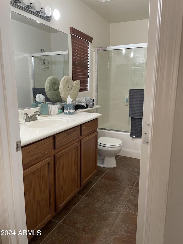 full bathroom featuring toilet, bath / shower combo with glass door, and vanity