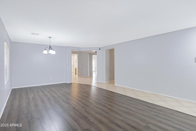 43232 W Magnolia Rd, Maricopa, AZ 85138 - empty room with a chandelier, wood finished floors, and baseboards