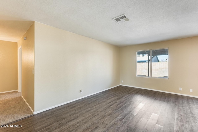 empty room with dark hardwood / wood-style flooring and a textured ceiling