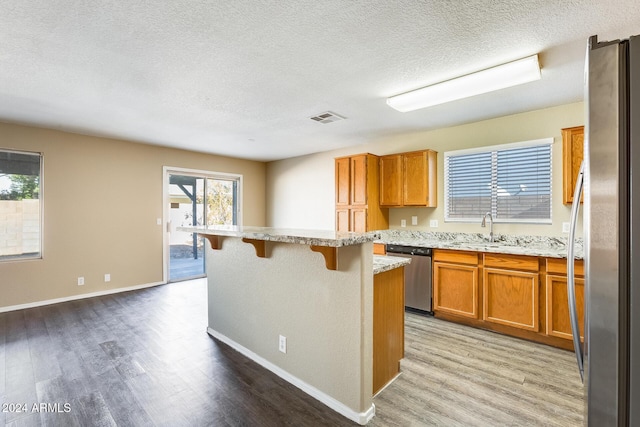 kitchen with sink, a center island, a kitchen breakfast bar, light hardwood / wood-style floors, and appliances with stainless steel finishes