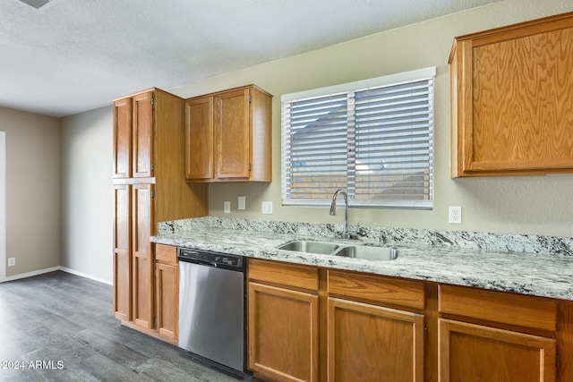 kitchen featuring dishwasher, dark hardwood / wood-style flooring, light stone counters, and sink