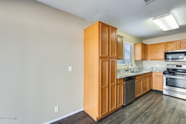 kitchen with dark wood-type flooring, light stone counters, sink, and stainless steel appliances