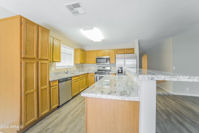 kitchen featuring stainless steel appliances, light hardwood / wood-style flooring, a kitchen island, and sink