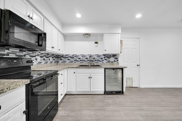 kitchen with sink, wine cooler, light stone counters, black appliances, and white cabinets