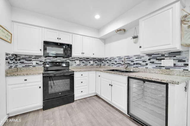 kitchen with sink, backsplash, white cabinets, light hardwood / wood-style floors, and black appliances