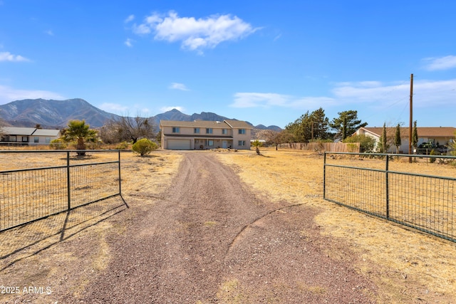 view of front of property with fence, a mountain view, and driveway