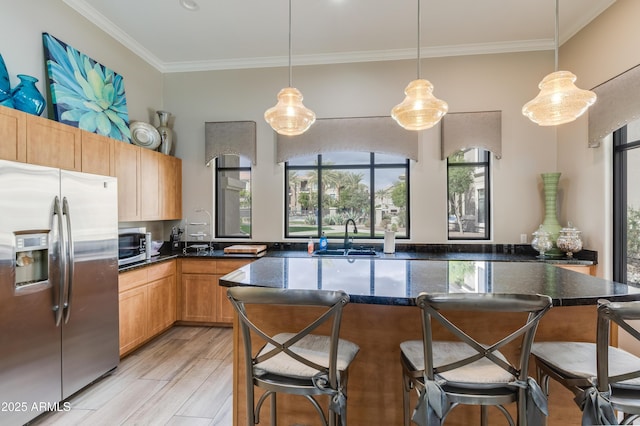 kitchen featuring light wood finished floors, stainless steel fridge with ice dispenser, a breakfast bar, ornamental molding, and a sink