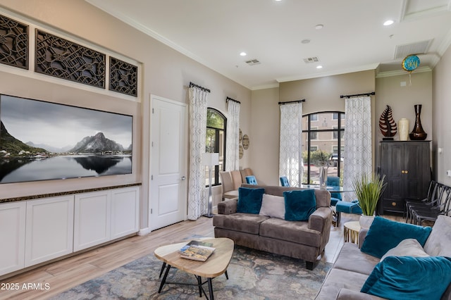 living room featuring visible vents, light wood-type flooring, and crown molding