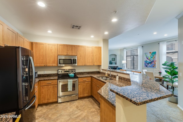 kitchen featuring visible vents, a peninsula, recessed lighting, a sink, and appliances with stainless steel finishes