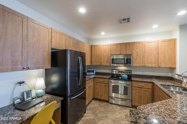 kitchen with visible vents, a sink, recessed lighting, dark stone counters, and appliances with stainless steel finishes