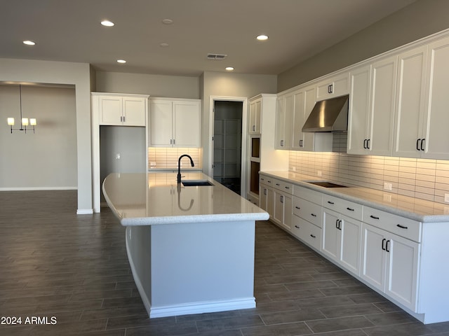 kitchen featuring white cabinets, sink, range hood, and an island with sink