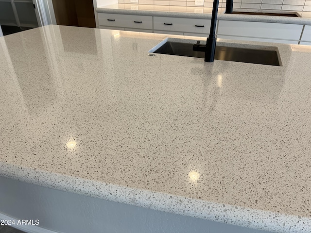 details featuring white cabinets, decorative backsplash, and sink