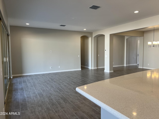 unfurnished room with a chandelier and dark hardwood / wood-style floors