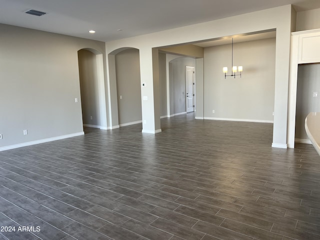 unfurnished living room with dark wood-type flooring and a notable chandelier