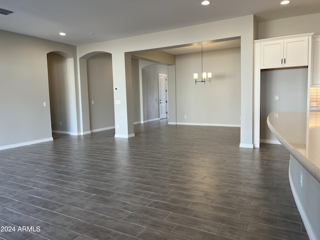 unfurnished living room with dark hardwood / wood-style flooring and an inviting chandelier