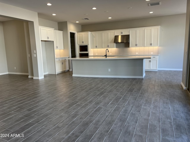 kitchen featuring dark hardwood / wood-style floors, white cabinetry, and a kitchen island with sink