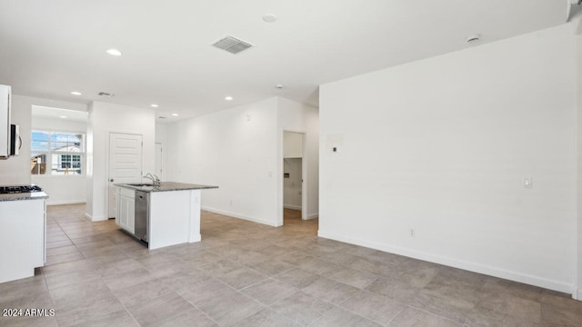 kitchen with stainless steel dishwasher, white cabinets, sink, and an island with sink