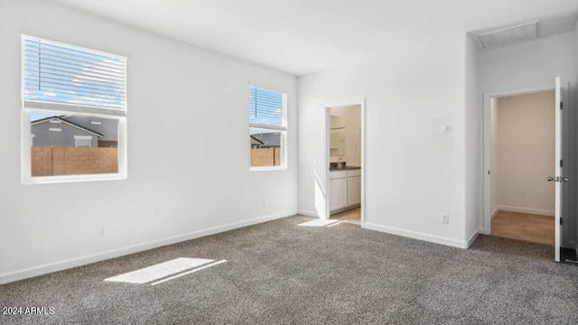 unfurnished bedroom featuring light carpet and ensuite bathroom