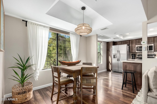 dining area with dark hardwood / wood-style flooring and a raised ceiling