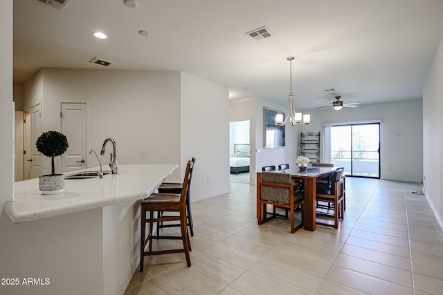 kitchen with visible vents, a sink, light tile patterned flooring, and light stone countertops