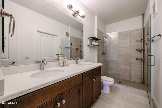 bathroom featuring double vanity, a sink, a stall shower, and toilet