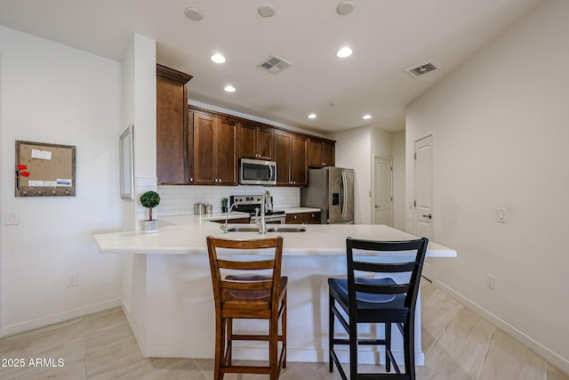 kitchen with visible vents, a peninsula, light countertops, a sink, and appliances with stainless steel finishes