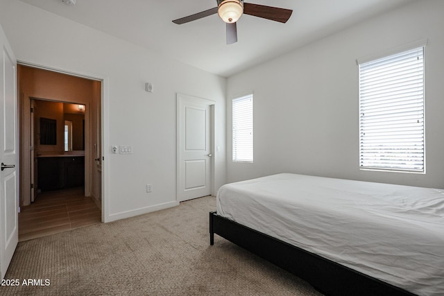 carpeted bedroom featuring connected bathroom, baseboards, and ceiling fan