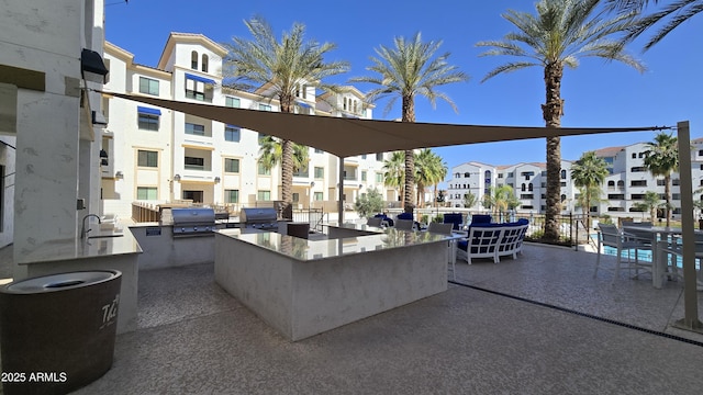view of patio / terrace featuring a residential view, outdoor wet bar, an outdoor kitchen, area for grilling, and a sink