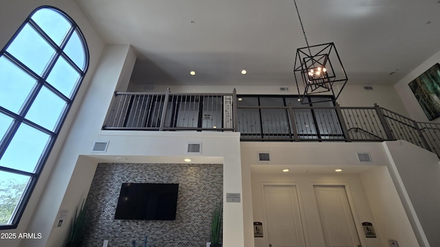 unfurnished living room featuring visible vents, plenty of natural light, a high ceiling, and a notable chandelier