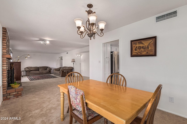 carpeted dining space featuring a textured ceiling, a notable chandelier, and a brick fireplace