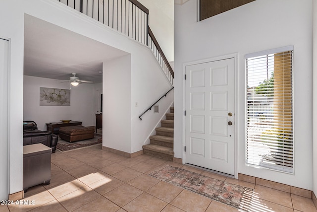 foyer entrance featuring light tile patterned floors, ceiling fan, and a towering ceiling