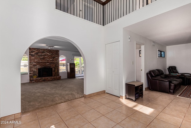 foyer entrance featuring a high ceiling, light colored carpet, and a fireplace