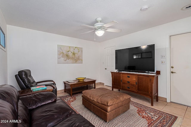 living room featuring a textured ceiling, light tile patterned floors, and ceiling fan