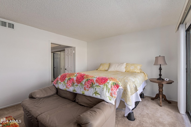 bedroom with light colored carpet and a textured ceiling