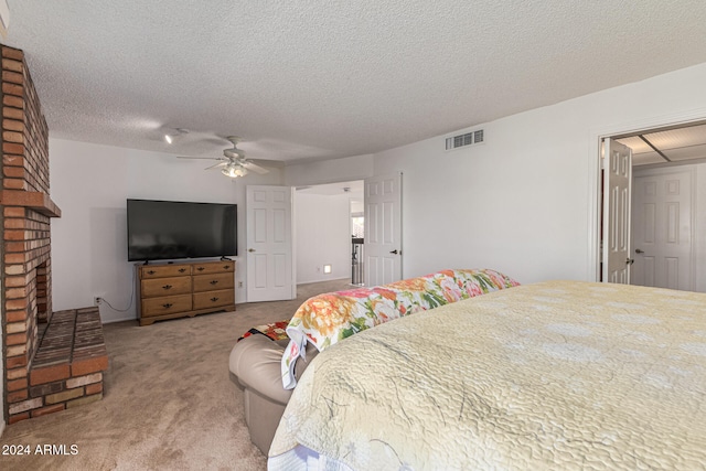 carpeted bedroom featuring a textured ceiling, ceiling fan, and a brick fireplace