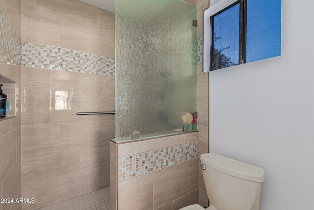 bathroom with tile walls, tile patterned flooring, toilet, and tiled shower