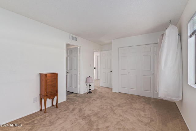 carpeted bedroom with a textured ceiling and a closet