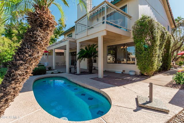 exterior space with a balcony, a patio, and a fenced in pool