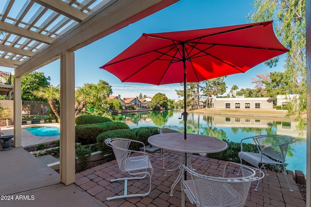 view of patio / terrace featuring a water view, a pergola, and a fenced in pool