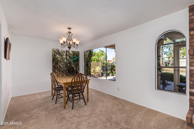 carpeted dining area featuring a textured ceiling and an inviting chandelier