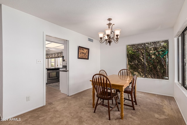 dining room with a chandelier, a textured ceiling, and light carpet