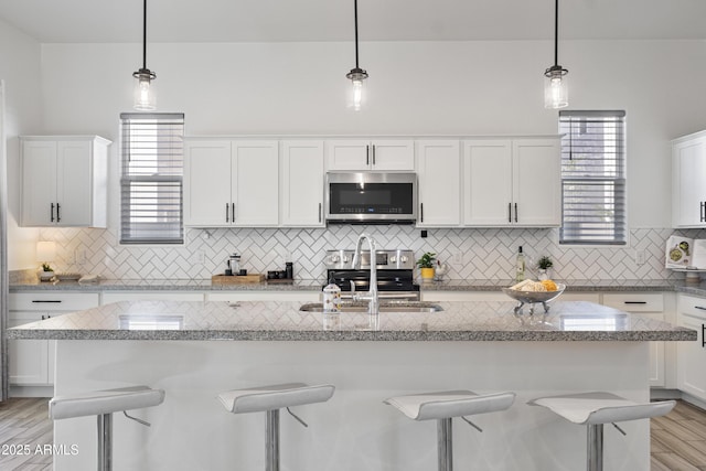 15718 W Polk St, Goodyear, AZ 85338 - kitchen with stainless steel appliances, white cabinetry, a kitchen bar, and a sink