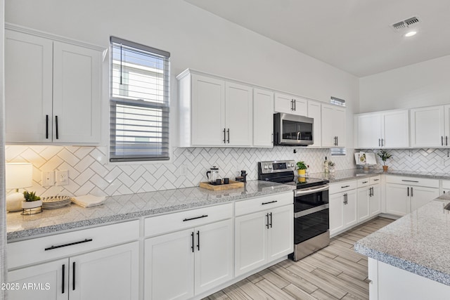 15718 W Polk St, Goodyear, AZ 85338 - kitchen with appliances with stainless steel finishes, white cabinets, backsplash, and light stone countertops
